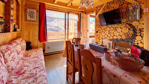 Un accogliente interno di una baita di legno, con zona pranzo, divano e camino.