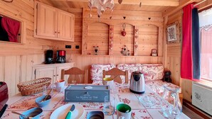 Una accogliente baita di legno con un tavolo da pranzo apparecchiato per quattro persone, una macchina da caffè e un bollitore.