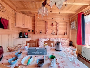 Ein gemütliches Holzhaus mit einem Esstisch für vier Personen, einer Kaffeemaschine und einem Wasserkocher.