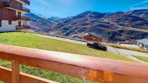 Un edificio moderno con balconi, una zona verde e montagne sullo sfondo.
