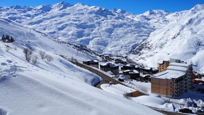 Un villaggio montano innevato con edifici e una pista da sci.