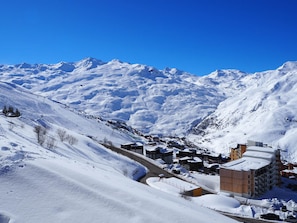 Ein verschneites Bergdorf mit Gebäuden und einer Skipiste.