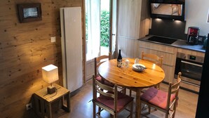 Une cuisine chaleureuse aux murs en bois, une table à manger avec des chaises et une petite table d’appoint avec une lampe.