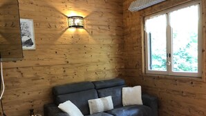 Une pièce chaleureuse avec un canapé en cuir foncé, une petite table en bois et une fenêtre donnant sur un paysage verdoyant.