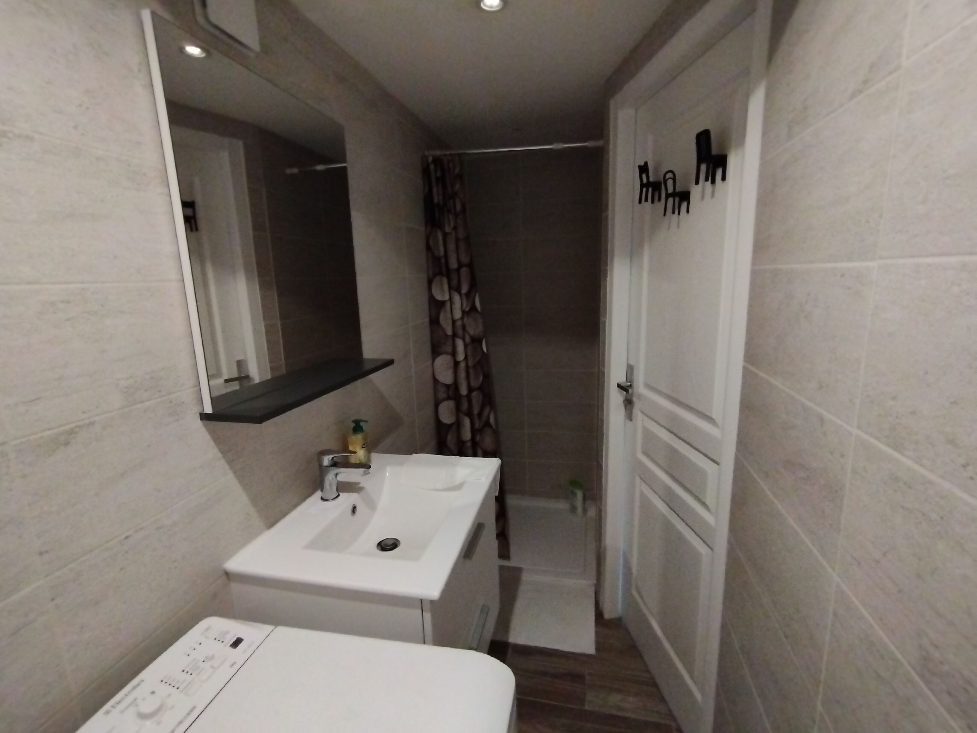 Un baño moderno con lavabo blanco, espejo y zona de ducha.