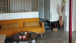 Ein Wohnzimmer mit einer Couch, einem Couchtisch mit Blumen und einer dekorativen Vase.