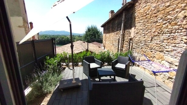 Eine Terrasse im Freien mit einer Steinmauer, einer Pergola und Gartenmöbeln.