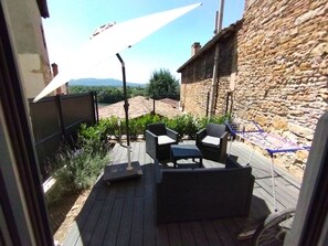 Un patio al aire libre con pared de piedra, una pérgola y mobiliario exterior.