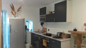 Eine kleine Küche mit Kühlschrank, Backofen, Mikrowelle und einer Kochinsel mit Spüle.