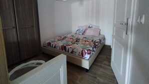Ein Schlafzimmer mit Bett, Kleiderschrank, Deckenventilator und einer Tür.