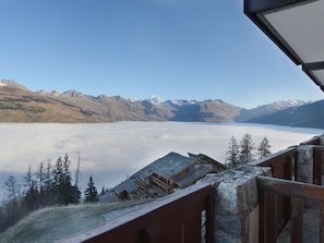 A mountain view with a wooden cabin and a stone railing.