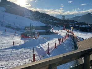 A ski resort with a chairlift, ski slopes, and buildings in the background.