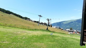 A grassy hillside with a ski lift and buildings in the background.