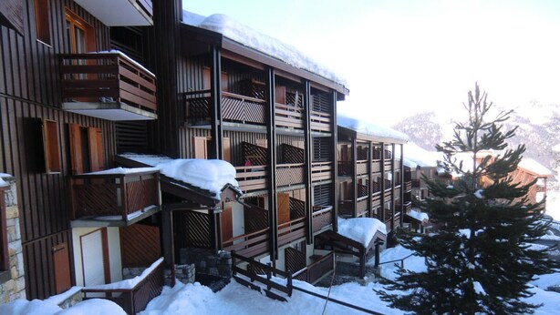 A multi-story building with wooden balconies and snow-covered railings.