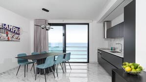 Una cucina moderna con vista sul mare, un'area pranzo con tavolo e sedie e una ciotola di frutta sul bancone.