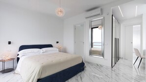 Una camera da letto moderna con un letto grande, un tavolino con una lampada e vista all'esterno da una grande finestra.