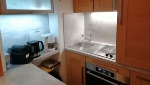 Une cuisine de taille réduite équipée d’un évier, d’une machine à café et d’un lave-vaisselle.