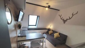 Ein kompakter Wohnraum mit einer Küchenzeile, einem Essbereich und einer Sitzecke mit Sofa und Fernseher.
