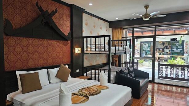 A hotel room with a large bed, a balcony with a view, and a ceiling fan. - Nanai 2 Residence Patong (Patong)