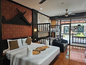 A hotel room with a large bed, a balcony with a view, and a ceiling fan.