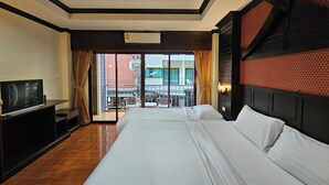 A hotel room with a large bed, a TV, and a balcony with a view of the city. - Nanai 2 Residence Patong (Patong)