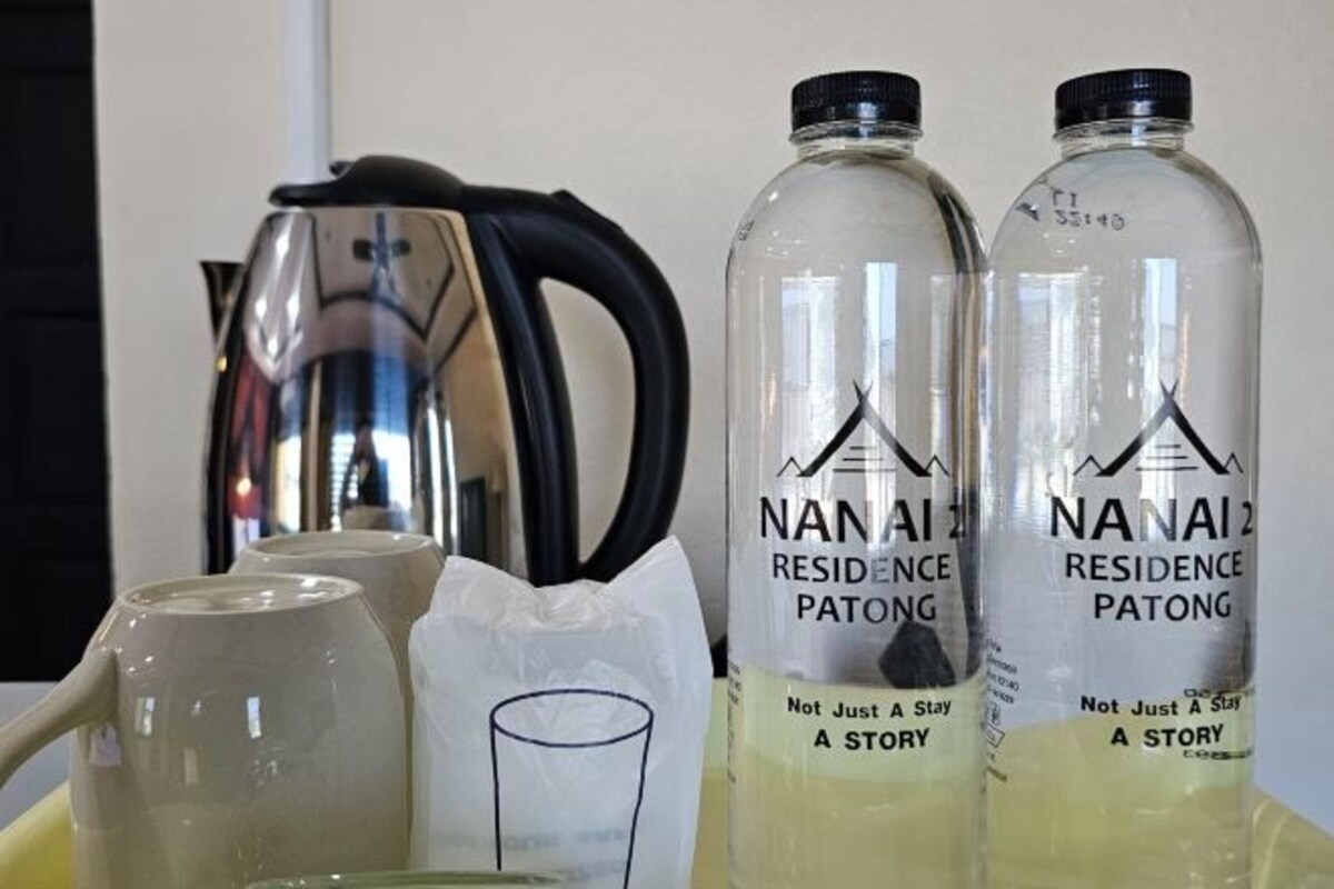 Deux bouteilles transparentes étiquetées « NANA AI Residence Patong » avec le slogan : « Plus qu’un simple séjour, une expérience inoubliable ».