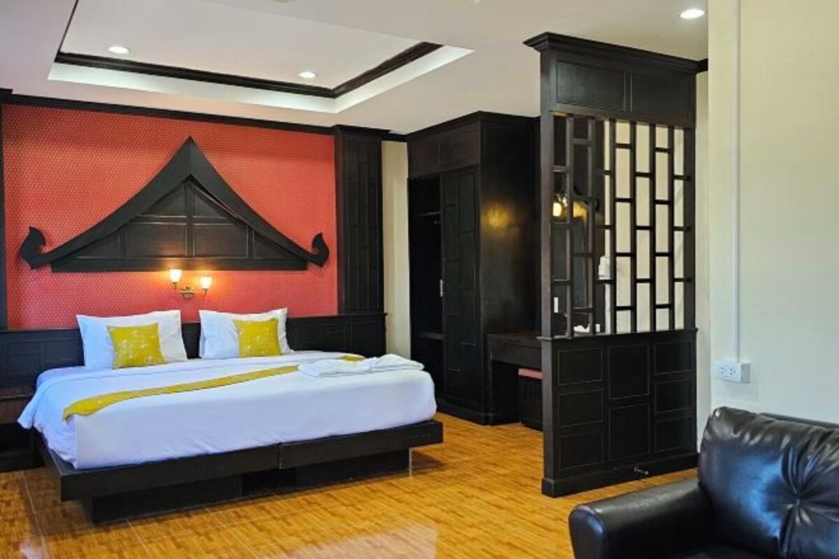 Une chambre d’hôtel avec un lit, une cloison noire et un fauteuil en cuir.