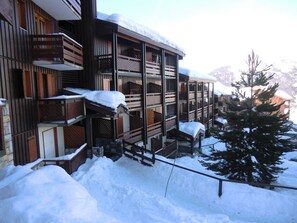 A multi-story building with wooden balconies and snow-covered railings.