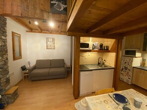A compact living space with a sofa, kitchenette, and a dining area.