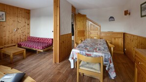 Une pièce en bois contenant un lit, une table, un banc et une armoire.