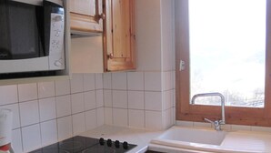 Une cuisine avec des carreaux blancs, une cuisinière, un four à micro-ondes, des armoires en bois et une fenêtre donnant sur un beau paysage.
