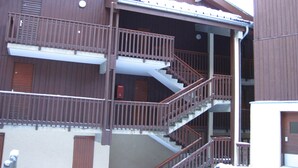 Un immeuble à plusieurs étages, doté d’une façade en bois, d’un escalier central et de balcons.