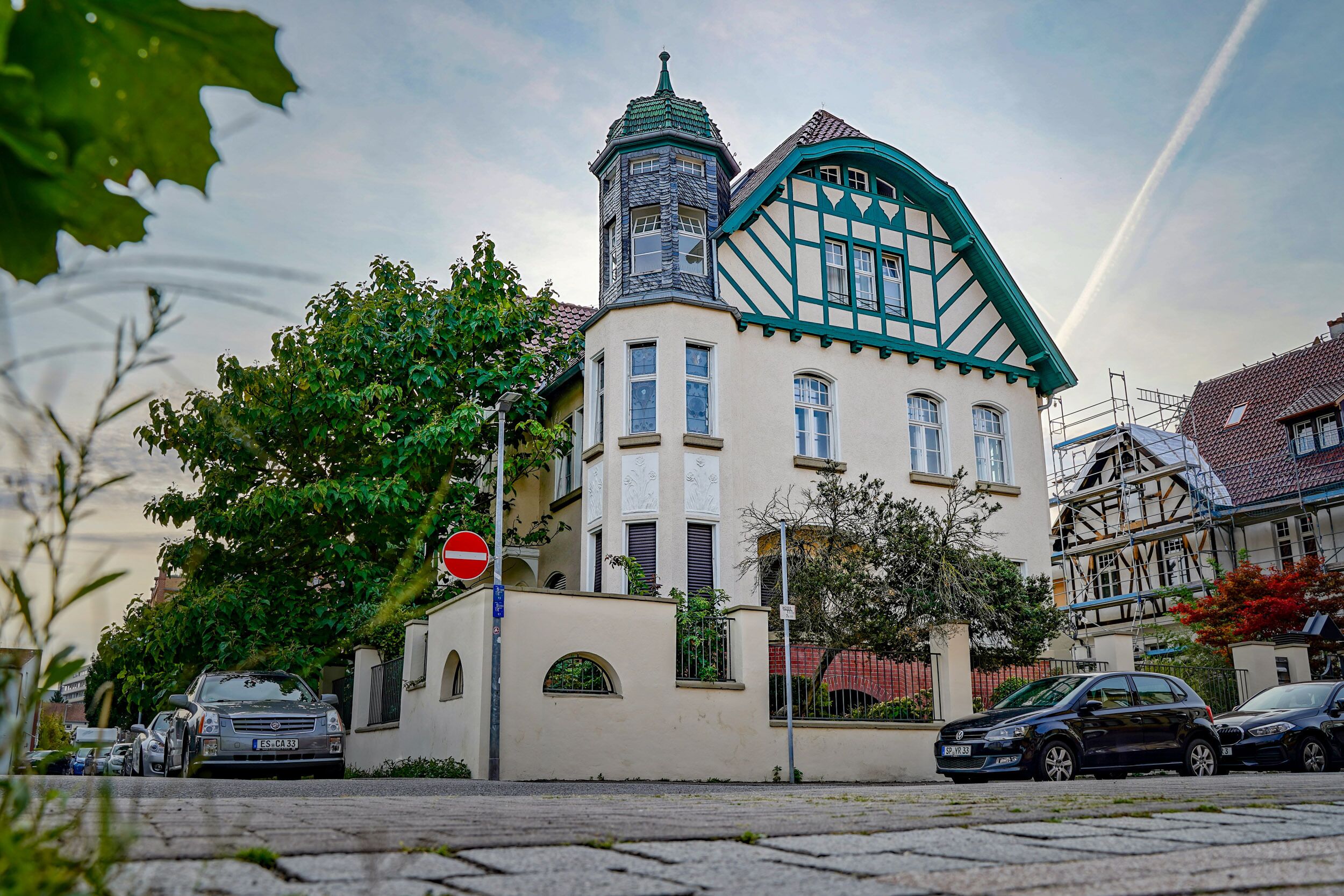 Um edifício tradicional com uma torre, portão e carros estacionados.