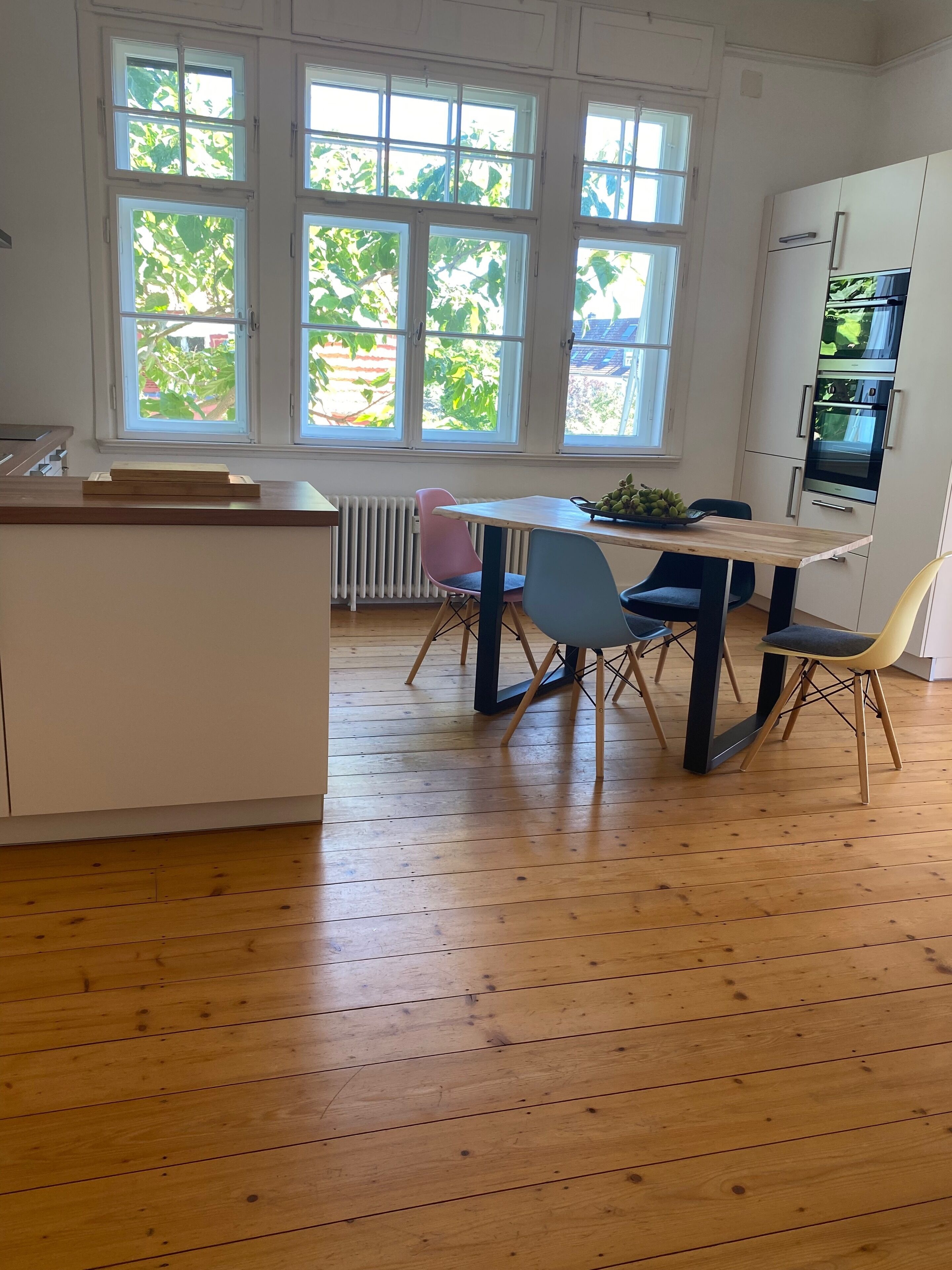 Een moderne keuken met een centraal eiland, een eettafel met stoelen en een inbouwoven.
