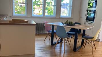 Een moderne keuken met een centraal eiland, een eettafel met stoelen en een inbouwoven.