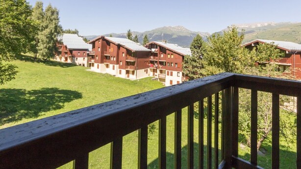 Un hotel con varias construcciones, una terraza de madera y montañas al fondo.