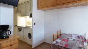 Una cocina funcional con lavadora, cafetera y muebles de madera.