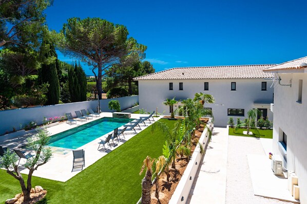 Une villa moderne dotée d’une piscine, d’une pelouse bien entretenue et surplombant un ciel d’un bleu éclatant.