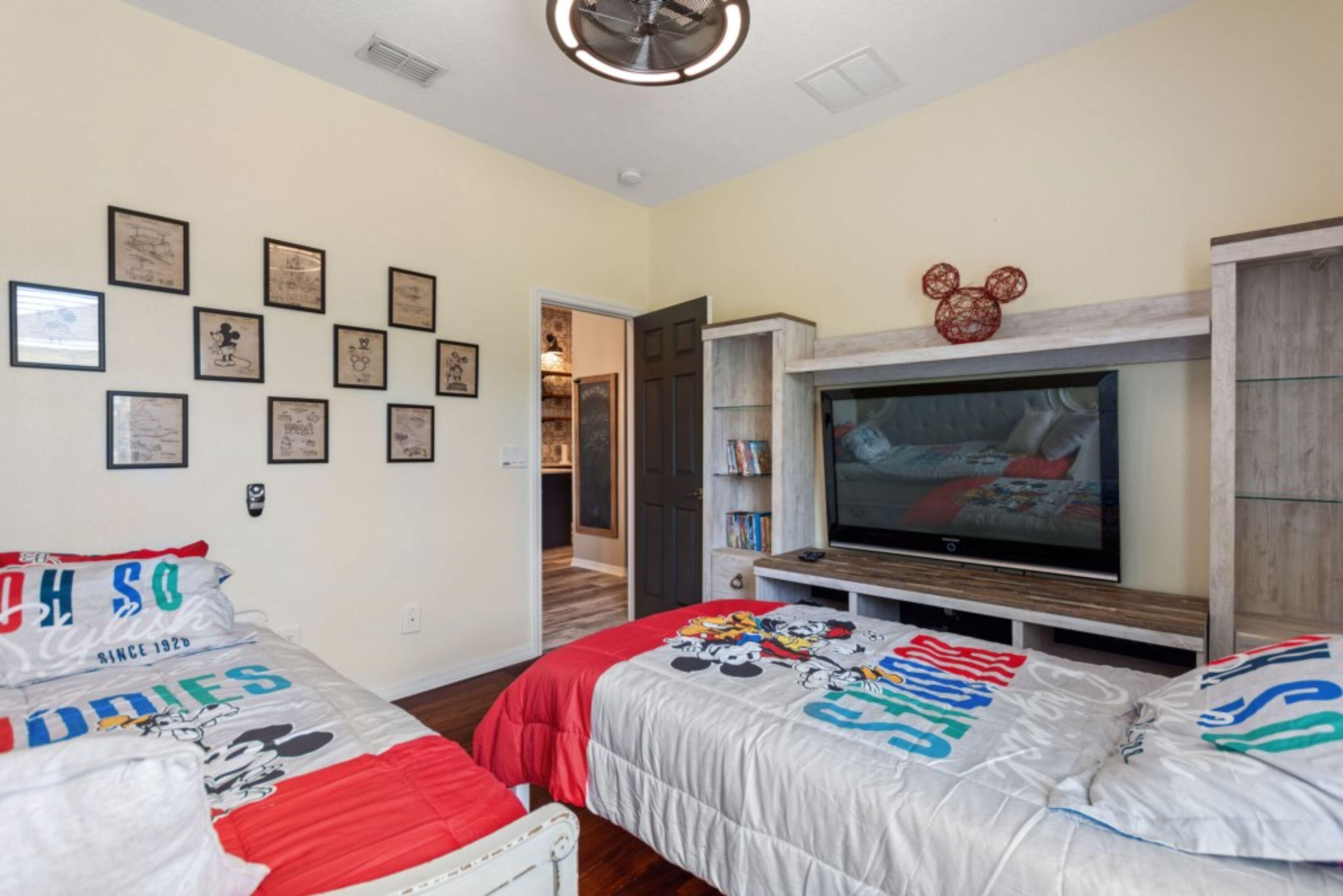 A bedroom with two beds, a television, and framed pictures on the wall.