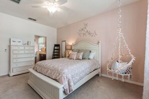 A bedroom with a bed, dresser, hanging chair, and decorative wall piece. - Serenity Now by Shine Villas at Watersong #416 (Davenport)