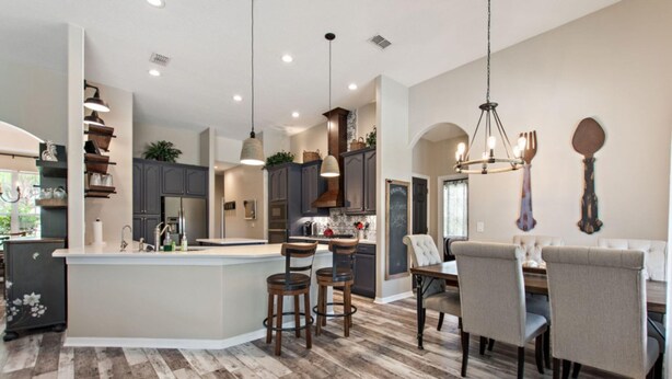 A spacious kitchen with a central island, dark wooden cabinets, and pendant lighting. - Serenity Now by Shine Villas at Watersong #416 (Davenport)