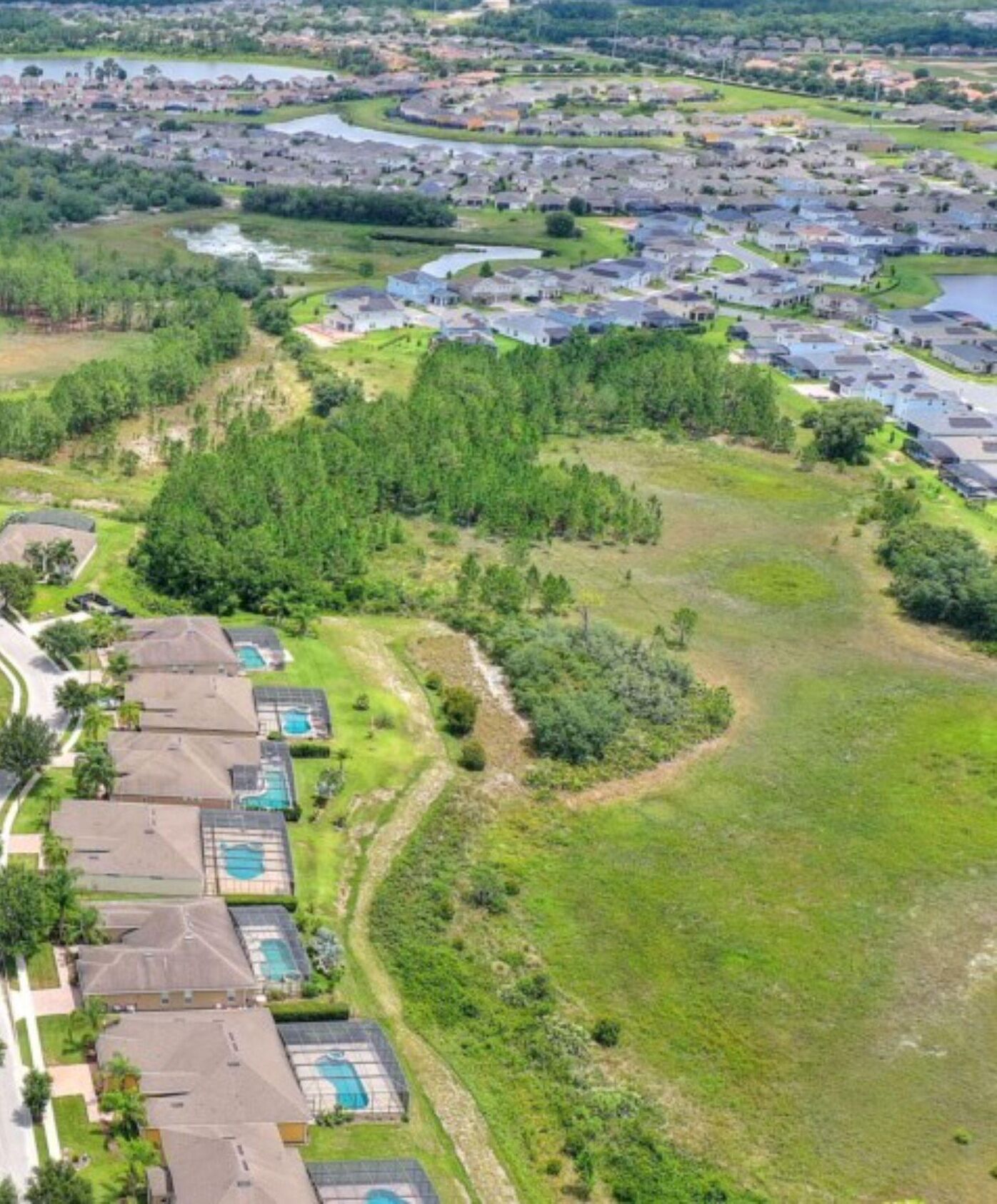 An aerial view of a residential area with houses, a river, and a large green park area.
