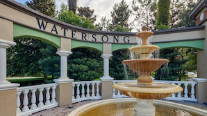 A multi-tiered fountain with water cascading down, set against a backdrop of a sign reading "WATERSONG". - Serenity Now by Shine Villas at Watersong #416 (Davenport)