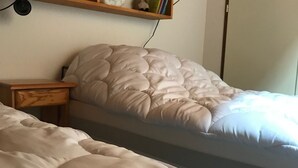 A bed with a white quilted headboard and a wooden nightstand beside it.
