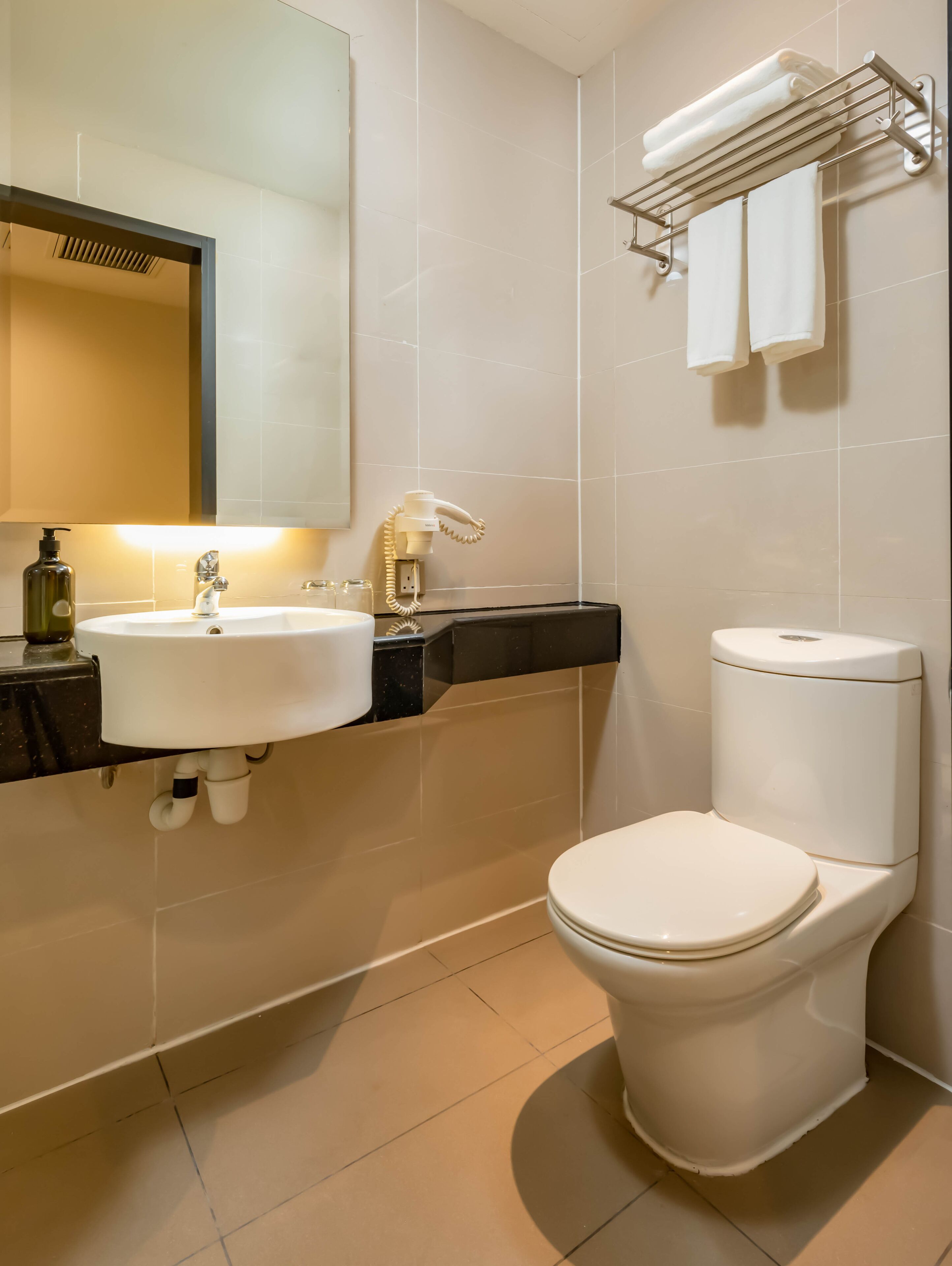 A modern bathroom with a white sink, mirror, and toilet.