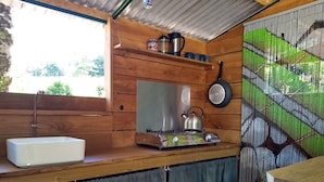 Cocina pequeña equipada con lavamanos, estufa, hervidor y ventana.