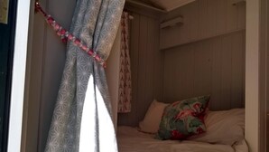 Un dormitorio con cama, ventana y cortinas estampadas.