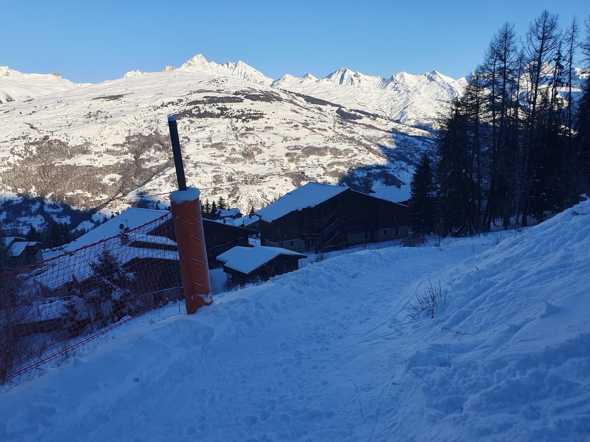 A snowy mountain landscape with a wooden building and a ski lift in the foreground.