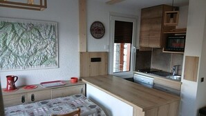 A compact kitchen with wooden cabinets, a built-in stove, and a dining area with a table and chairs.