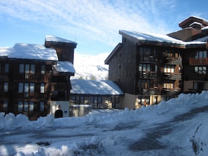 Un edificio cubierto de nieve con varios balcones y una base de piedra, rodeado de nieve.